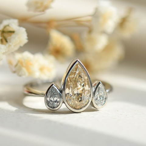 champagne diamond with two white diamond side stones bezel set platinum ring