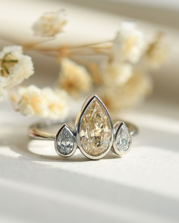 champagne diamond with two white diamond side stones bezel set platinum ring