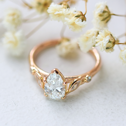 lab-grown pear diamond with marquise and round natural diamond side stones in 18k rose gold