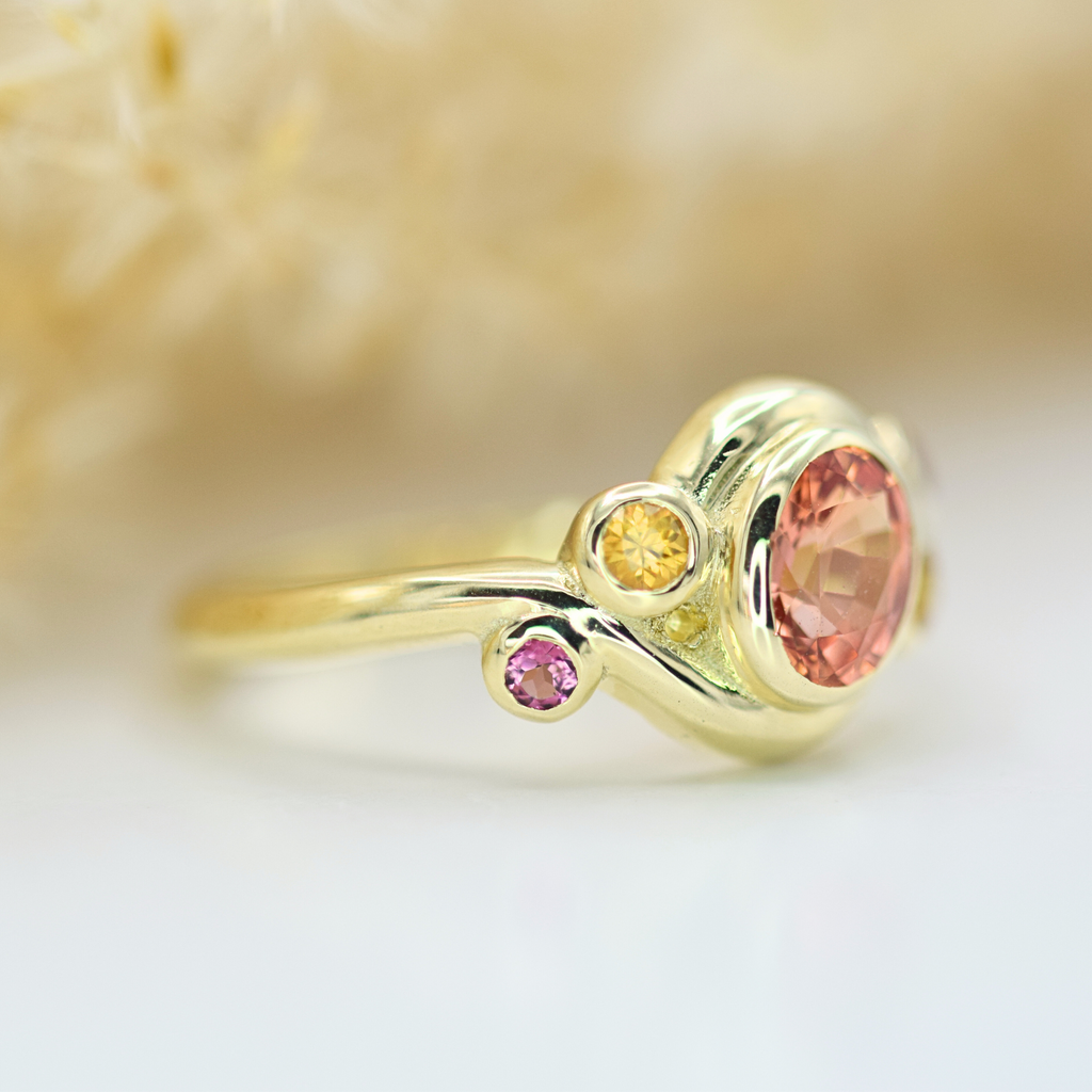 oval peach padparadscha with yellow and purple sapphire side stones in 14k yellow gold chunky ring side shot