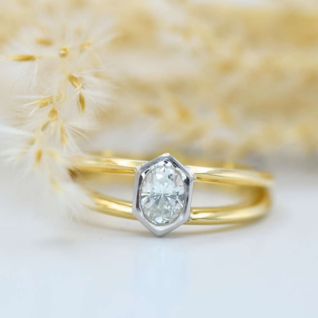 oval white diamond in a hexagonal frame on a double band yellow gold ring