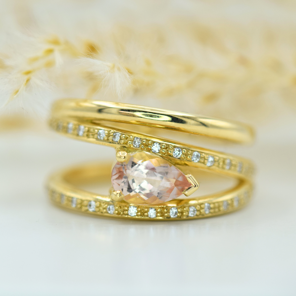 peach pear cut morganite set horizontally on wrap around diamond set gold ring