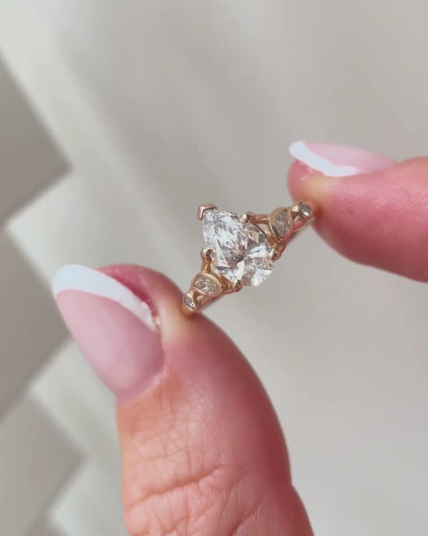 lab-grown pear diamond with marquise and round natural diamond side stones in 18k rose gold - in hand