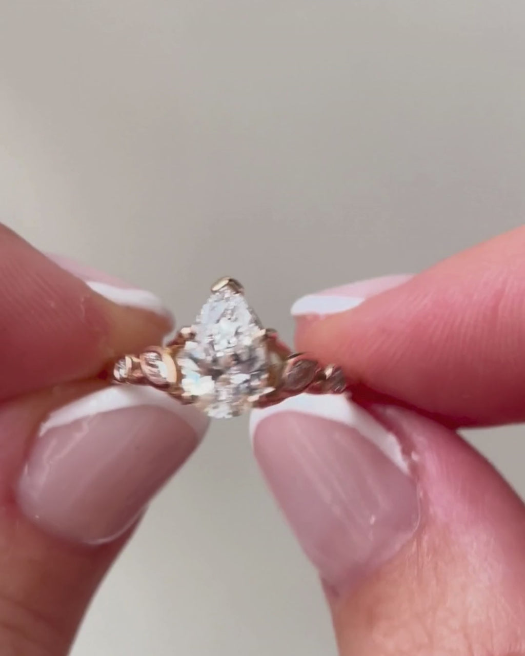 lab-grown pear diamond with marquise and round natural diamond side stones in 18k rose gold in hands