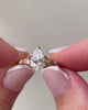 lab-grown pear diamond with marquise and round natural diamond side stones in 18k rose gold in hands