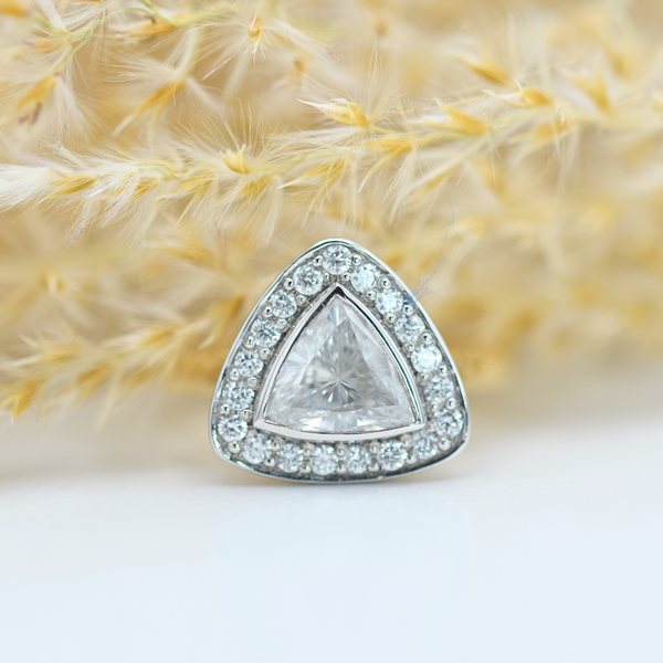 A yellow gold ring with a platinum setting, featuring a trillion cut diamond center stone surrounded by a halo of round brilliant cut diamonds.